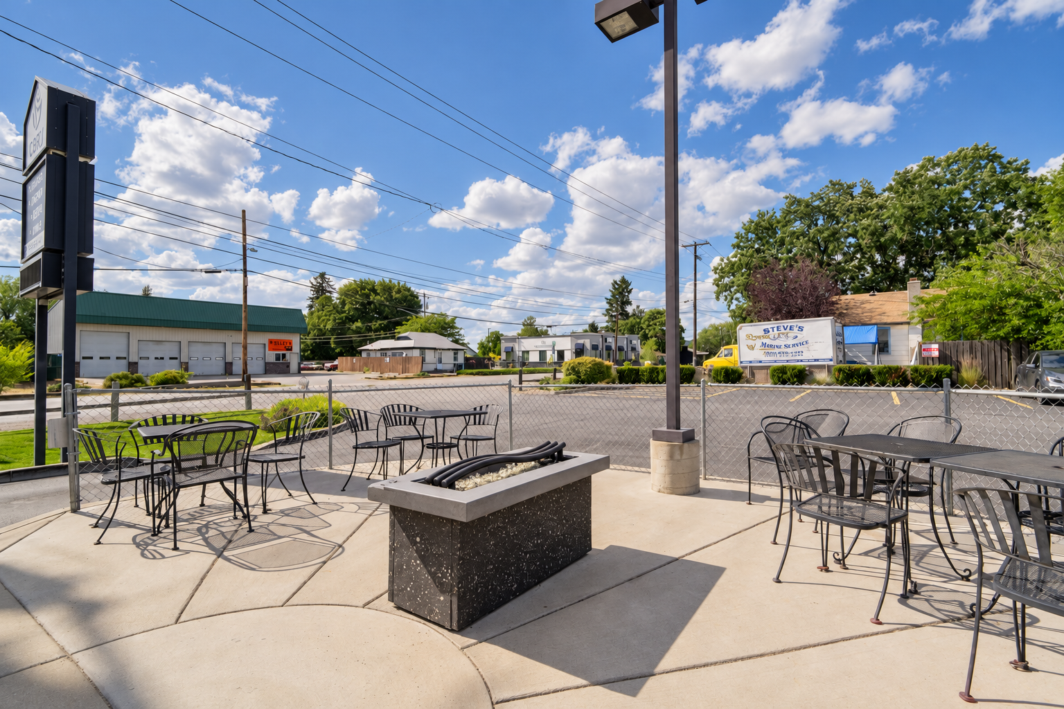 Cozy Coffee’s fenced patio with metal tables, chairs and a gas fire pit
