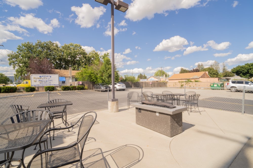 The fenced patio with tables and a gas fire pit
